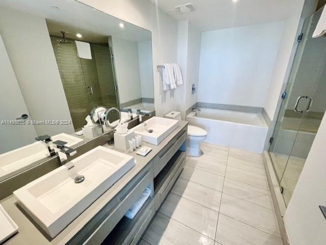 full bathroom featuring toilet, double vanity, separate shower and tub, and tile floors