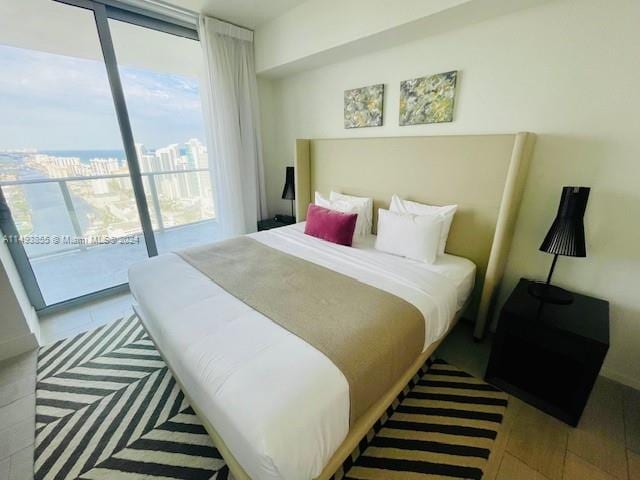 bedroom featuring expansive windows, access to exterior, and light hardwood / wood-style flooring