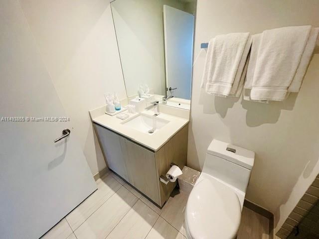 bathroom with toilet, tile floors, and vanity