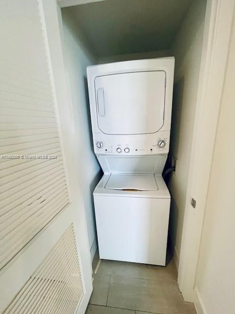 laundry area with light tile floors and stacked washer and clothes dryer