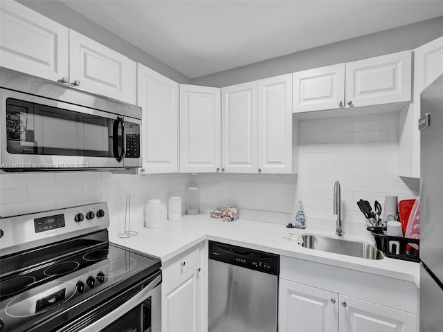 kitchen with tasteful backsplash, white cabinets, appliances with stainless steel finishes, and sink