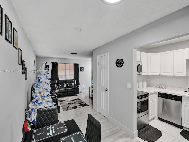 kitchen with white cabinets, tasteful backsplash, light tile floors, and appliances with stainless steel finishes