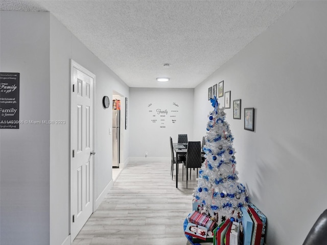 hall with a textured ceiling and light wood-type flooring