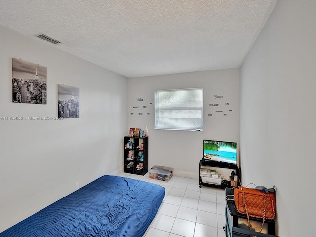 bedroom with light tile floors and a textured ceiling