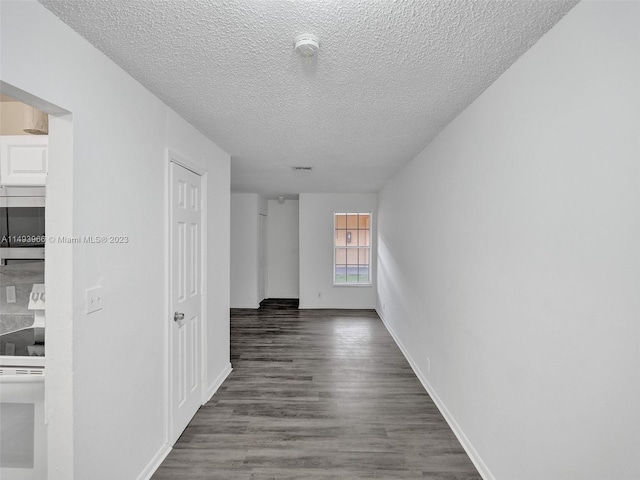 corridor featuring a textured ceiling and dark hardwood / wood-style floors