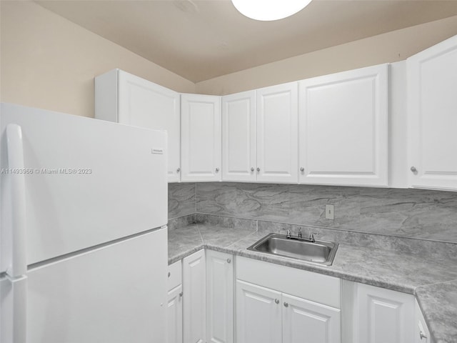 kitchen with backsplash, white cabinets, white fridge, and sink