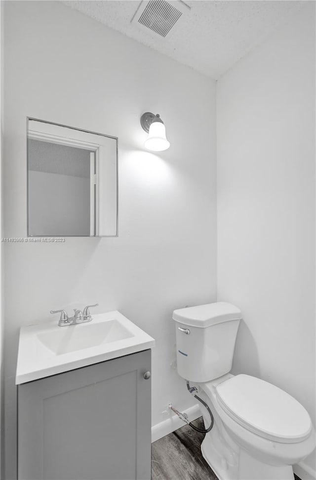 bathroom featuring toilet, a textured ceiling, vanity, and wood-type flooring