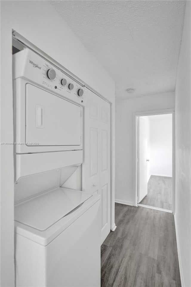 clothes washing area featuring stacked washing maching and dryer and hardwood / wood-style flooring