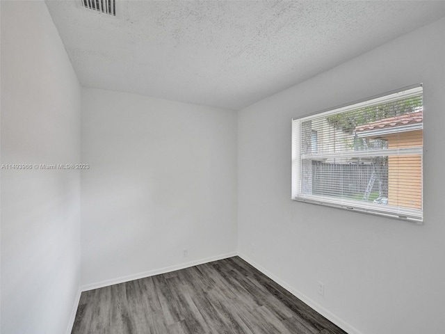 unfurnished room with a textured ceiling and dark hardwood / wood-style floors