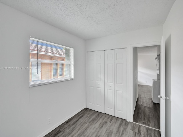 unfurnished bedroom featuring a closet, a textured ceiling, and dark wood-type flooring