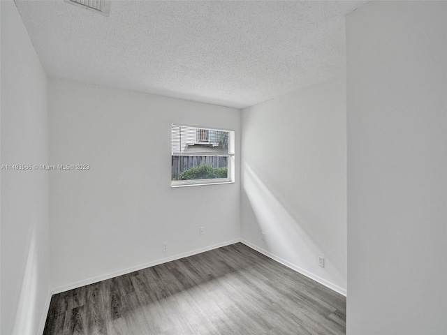 spare room featuring dark hardwood / wood-style floors and a textured ceiling