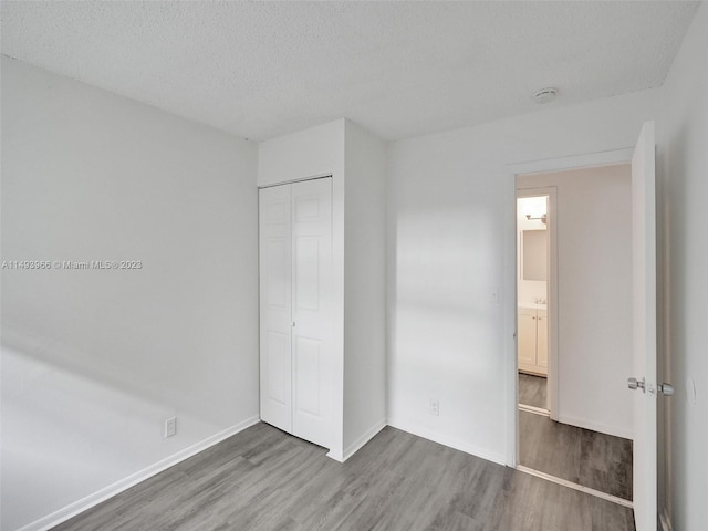 unfurnished bedroom with a closet, dark wood-type flooring, and a textured ceiling