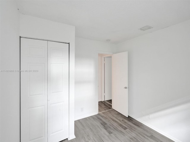 unfurnished bedroom with a closet and light hardwood / wood-style floors