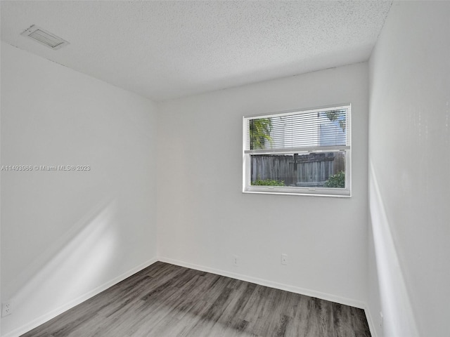 unfurnished room featuring a textured ceiling and dark hardwood / wood-style floors