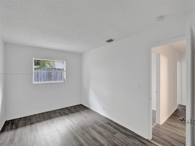 unfurnished room featuring a textured ceiling and dark hardwood / wood-style flooring