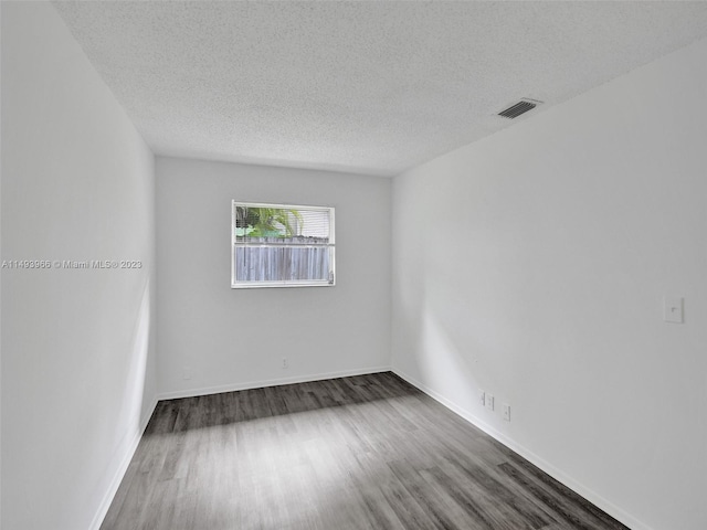 empty room with a textured ceiling and dark hardwood / wood-style flooring