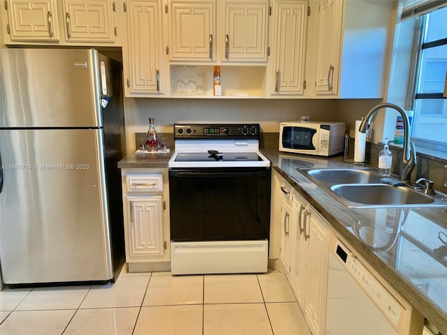 kitchen with white appliances, sink, dark stone counters, and light tile flooring