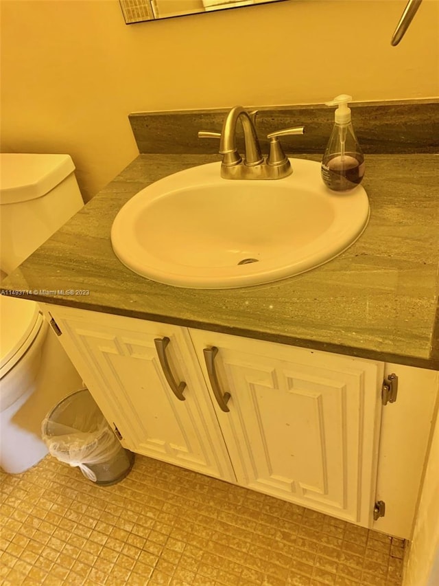 bathroom with toilet, tile flooring, and vanity