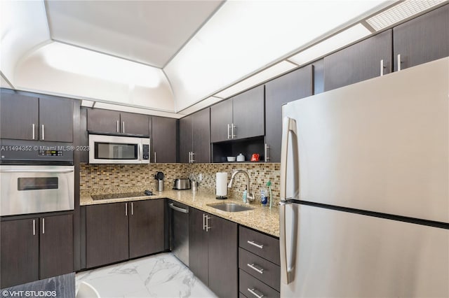 kitchen featuring appliances with stainless steel finishes, light stone counters, backsplash, and sink