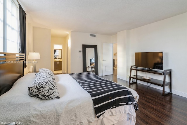 bedroom with connected bathroom and dark hardwood / wood-style floors