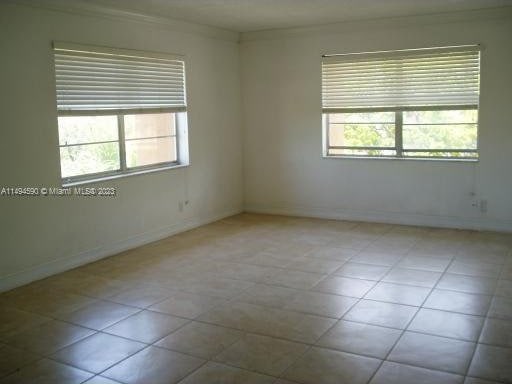 tiled empty room with a healthy amount of sunlight and crown molding