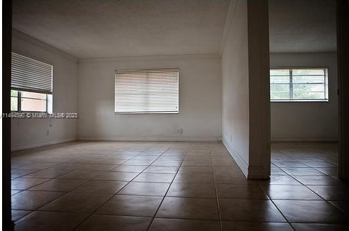 empty room featuring crown molding and dark tile patterned flooring