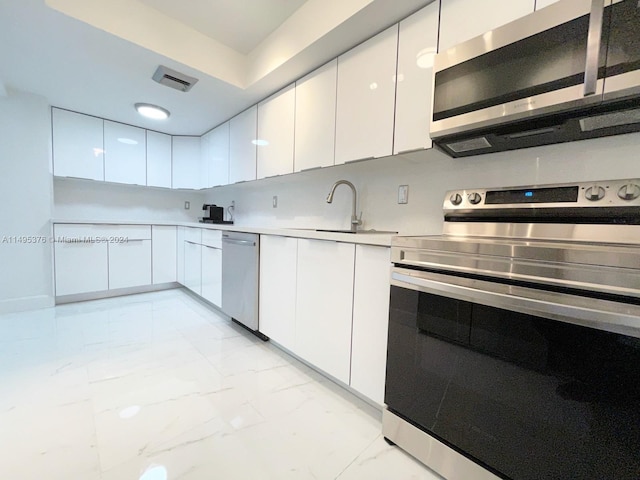 kitchen with sink, white cabinetry, light tile patterned flooring, and stainless steel appliances