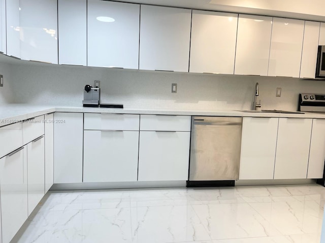 kitchen with tasteful backsplash, stainless steel appliances, white cabinets, sink, and light tile patterned floors