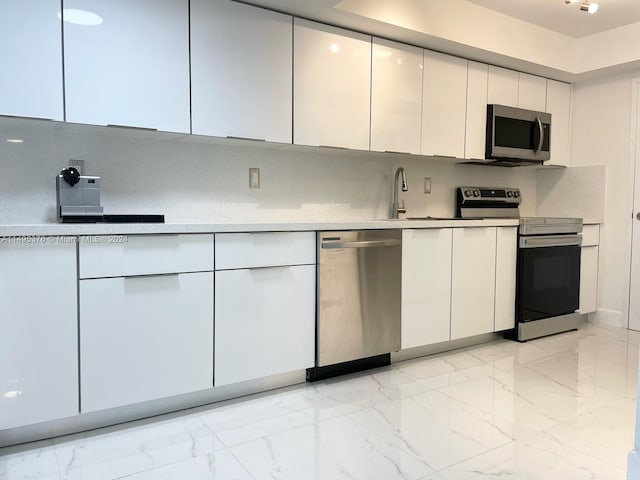 kitchen featuring decorative backsplash, stainless steel appliances, light tile patterned floors, and white cabinets