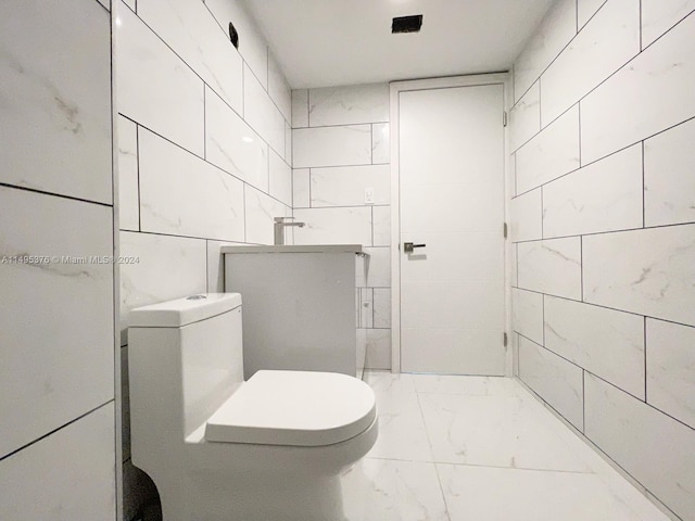 bathroom featuring tile walls and toilet