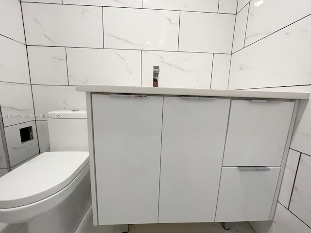 bathroom with toilet and tile walls