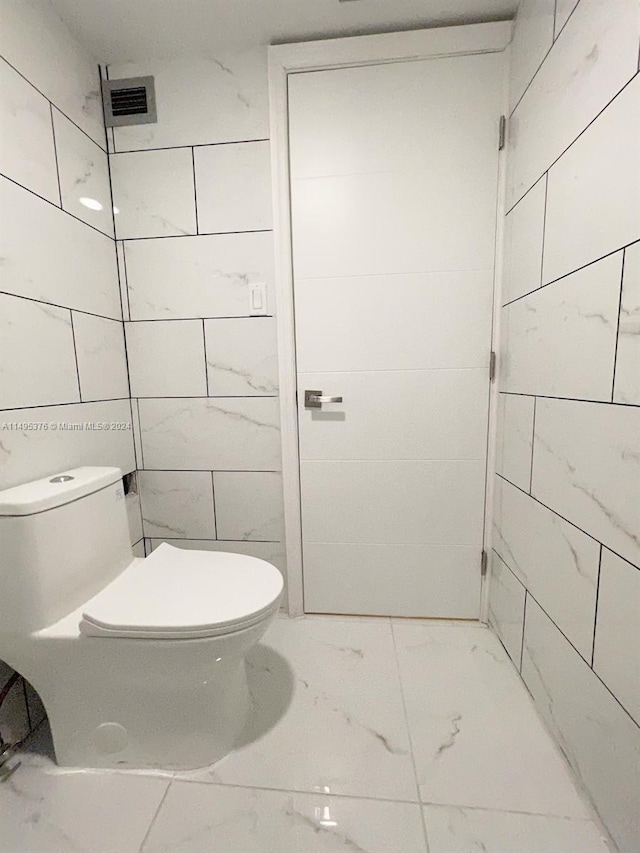 bathroom with tile walls and toilet