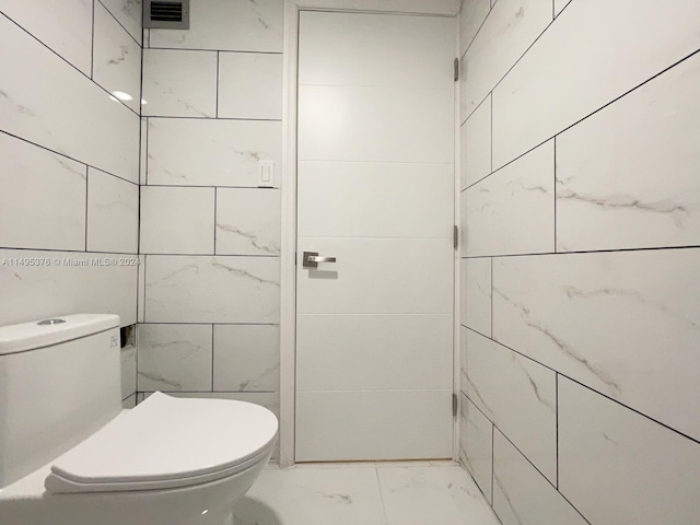 bathroom featuring tile patterned floors, tile walls, and toilet