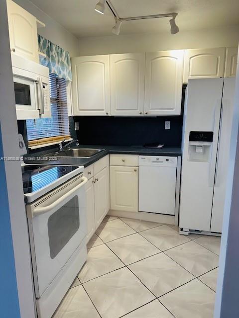 kitchen with sink, backsplash, white cabinets, track lighting, and white appliances