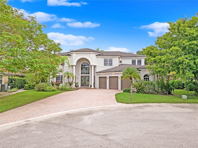 mediterranean / spanish-style home featuring a front yard, central AC, and a garage