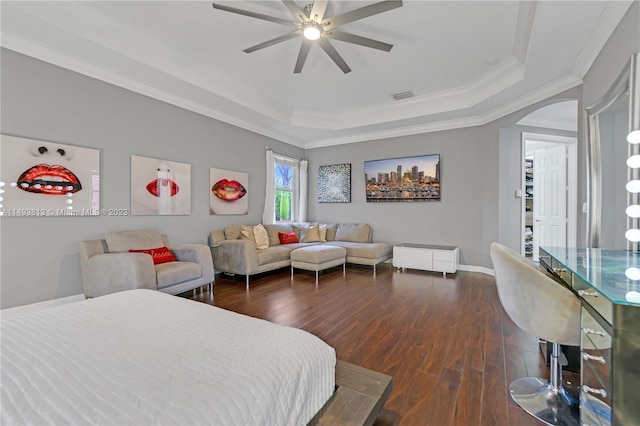 bedroom featuring ceiling fan, dark hardwood / wood-style flooring, ornamental molding, and a tray ceiling