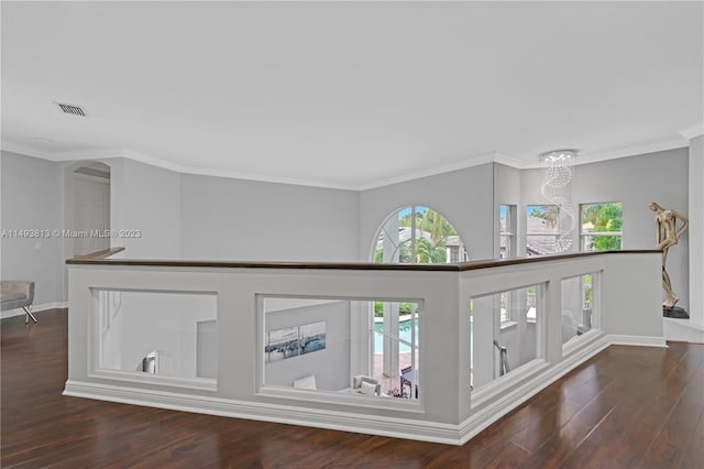 hall featuring crown molding, dark wood-type flooring, and a chandelier