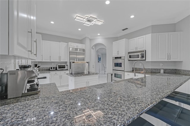 kitchen featuring stone counters, stainless steel appliances, and white cabinetry