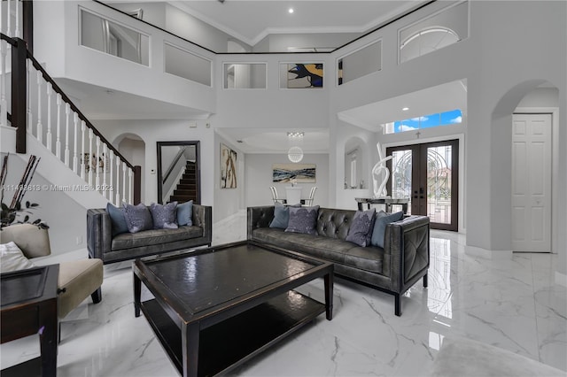 living room featuring ornamental molding, a towering ceiling, and french doors