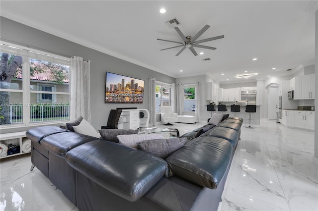 living room with ceiling fan, a healthy amount of sunlight, and ornamental molding