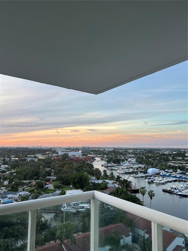 balcony at dusk featuring a water view