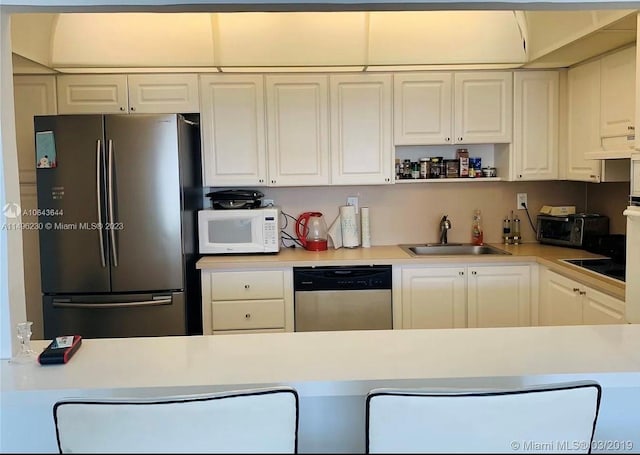 kitchen with white cabinets, premium range hood, stainless steel appliances, and sink