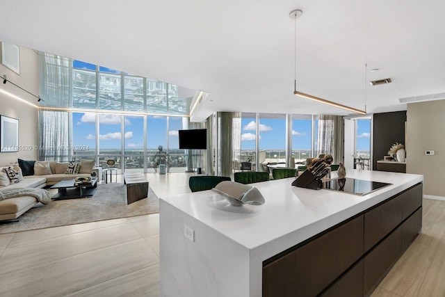 kitchen with dark brown cabinetry, decorative light fixtures, expansive windows, and black electric stovetop