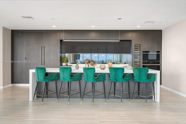 kitchen featuring a kitchen breakfast bar, double oven, and a kitchen island with sink