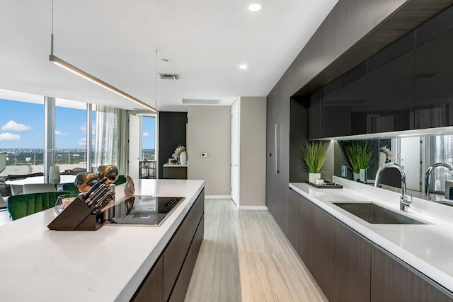 kitchen featuring dark brown cabinetry, sink, expansive windows, and light tile floors