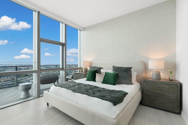 bedroom with light hardwood / wood-style flooring and a wall of windows