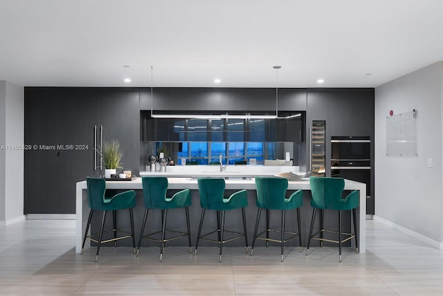 kitchen featuring a kitchen island, a kitchen breakfast bar, double oven, and decorative light fixtures