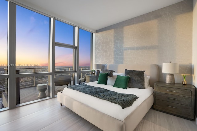 bedroom with light wood-type flooring and expansive windows