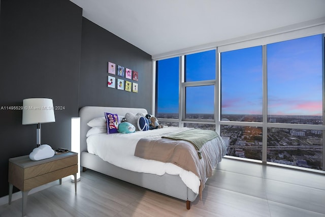 bedroom with expansive windows and hardwood / wood-style flooring