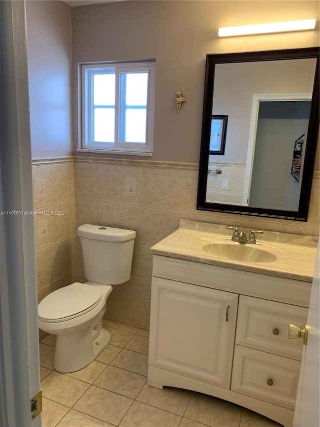 bathroom with vanity, toilet, and tile walls